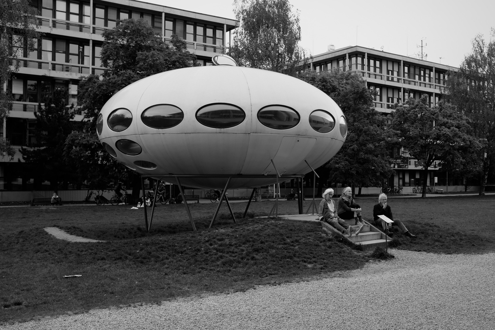 UFO-like house; a white capsule with round windows, with small people in front of it