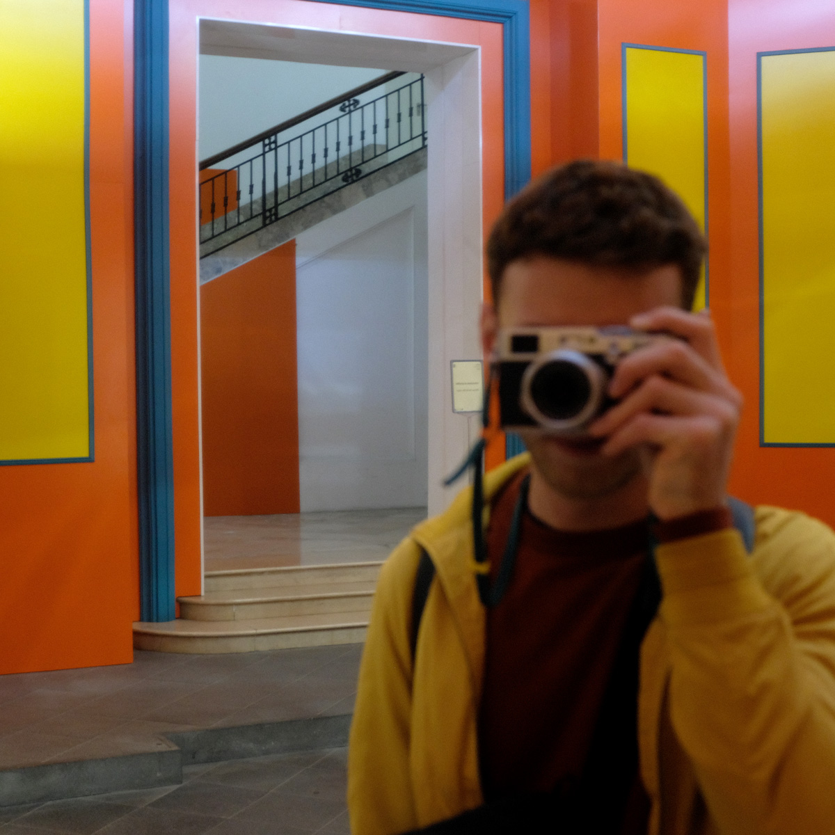 Me standing in a colorful room, taking my photo in the mirror, camera in front of my face